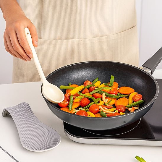personne qui cuisine avec le repose cuillère​ à côté