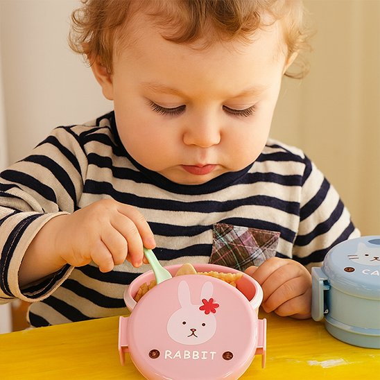 Petite fille qui mange dans le lunch box enfant rose